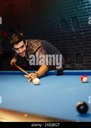 Ein Mann, der versucht, den Ball im Billard am Zimmerpool in der Bar zu schlagen Stockfoto