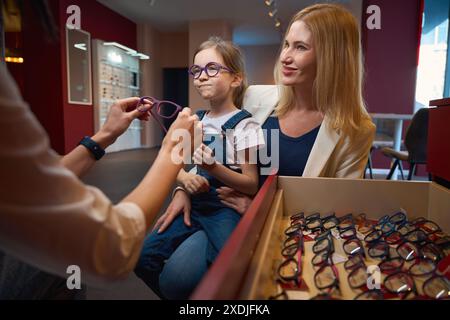 Der Berater hilft, einen bequemen Rahmen für das kleine Mädchen zu wählen Stockfoto