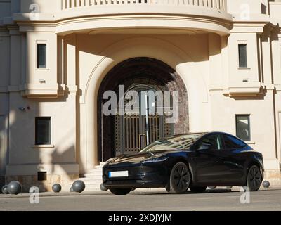 Bukarest, Rumänien - 16. Mai 2024: Tesla Elektroauto parkt vor dem Eingang des Institutionengebäudes mit einer wunderschönen massiven Tür im alten Zentrum von BU Stockfoto