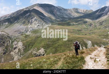 Fotograf macht Fotos in einer Berglandschaft, die Landschaft ist in den Pyrenäen, er macht Fotos mit einem Teleobjektiv Stockfoto