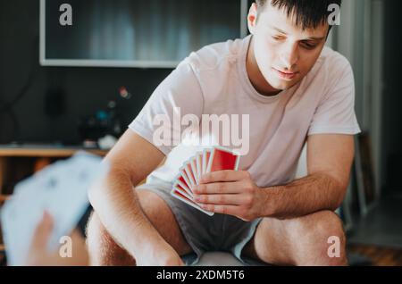 Junger Mann, der zu Hause mit Familie oder Freunden Karten spielt Stockfoto