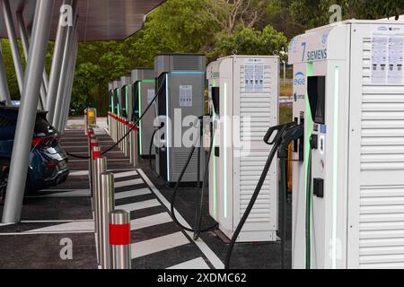 La Turbie, Frankreich - 12. Juni 2023: Mehrere Ladegeräte für Elektrofahrzeuge stehen auf einem Außenparkplatz, mit Kabeln, die mit einem geparkten Auto verbunden sind Stockfoto