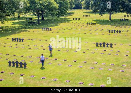 Deutscher Militärfriedhof in der Normandie, Frankreich, mit Besuchern, die sich unter sonnigem Himmel über die Reihen von Gräbern nachdenken. Stockfoto