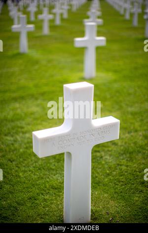 Weißes Kreuz für einen unbekannten Soldaten auf dem amerikanischen Militärfriedhof in der Normandie, Frankreich, das gefallene Soldaten mit Reihen von Gräbern auf grünem Gras ehrt. Stockfoto