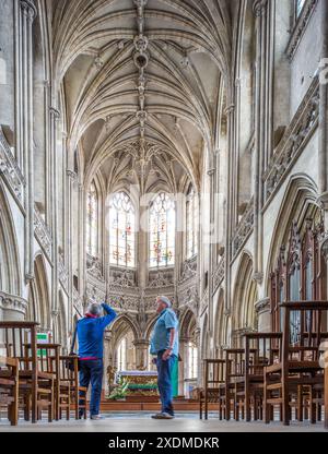 Foto des großen Innenraums von Eglise Saint Pierre in Caen, Normandie, Frankreich, mit wunderschöner gotischer Architektur und zwei Personen, die die bewundern Stockfoto