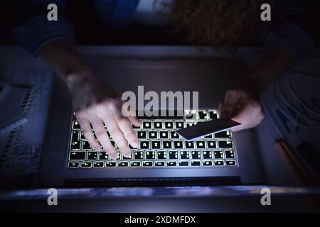 Kreditkarte in der Hand halten und Laptop benutzen. Stockfoto