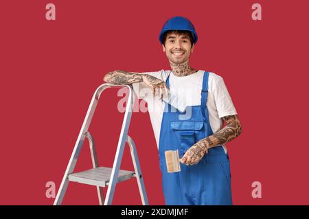 Männlicher Maler mit Palettenmustern, Pinsel und Leiter auf farbigem Hintergrund Stockfoto