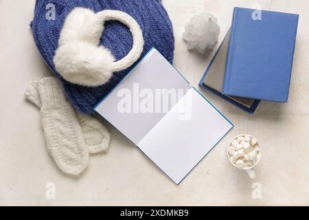 Tasse Kakao mit Büchern und Winterkleidung auf weißem Hintergrund Stockfoto