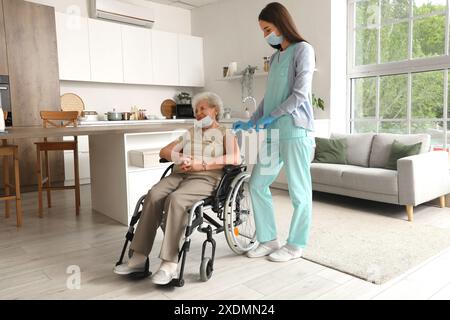 Krankenschwester impfende Seniorin im Rollstuhl zu Hause Stockfoto
