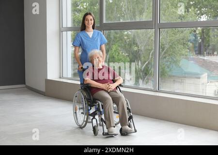 Seniorin im Rollstuhl mit Krankenschwester drinnen Stockfoto