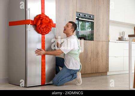 Junger Mann mit Geschenkkühlschrank in der Küche Stockfoto
