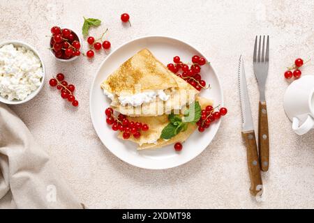 Crepes oder dünne Pfannkuchen mit Käsehütte oder Quark und frischen roten Johannisbeerbeeren, Blick von oben Stockfoto