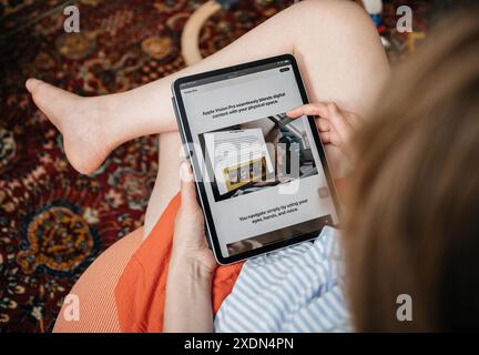 London, Großbritannien - 11. Juni 2023: Eine Frau in ihrem gemütlichen Wohnzimmer liest über das Apple Vision Pro Mixed-Reality-Headset auf ihrem iPad Pro, Focusin Stockfoto