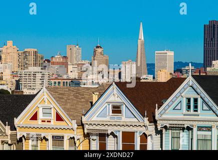 Reihe viktorianischer Häuser, bekannt als die „Painted Ladies“, Alamo Square Park mit der City Skyline in der Ferne, San Francisco, Kalifornien, USA Stockfoto