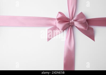 Pinkes Satinband mit Schleife auf weißem Hintergrund, Draufsicht Stockfoto