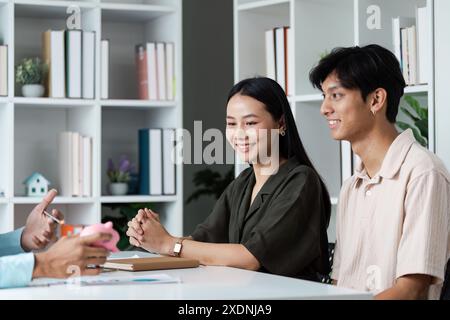 Junges Paar diskutiert mit professionellem Berater über Investitionen in Finanzpläne in modernem Büroumfeld Stockfoto