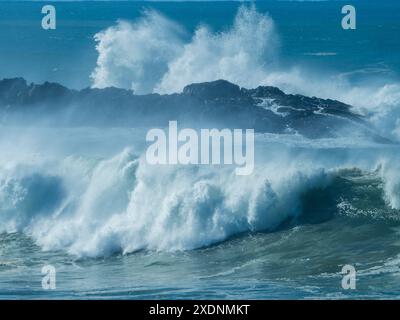 Wilde, große Wellen, die über Felsen krachen und vor einer Insel brechen, große Brandung, die einen nebeligen Nebel von Sea Spray verursacht, Mid North Coast NSW Australien Stockfoto