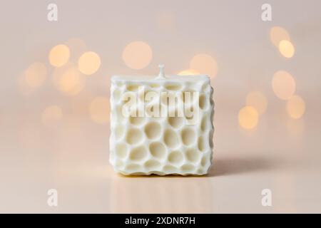 Handgefertigte Kerze aus Sojabohnenwachs auf pastellrosa Hintergrund mit Bokeh und Kopierraum. Stockfoto