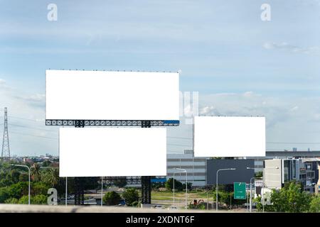 Ein großes, leeres Plakat an der Seite einer Autobahn. Die Reklametafel ist weiß. Es liegt in einer ländlichen Gegend mit Bäumen und Gras im Hintergrund. Die Stockfoto