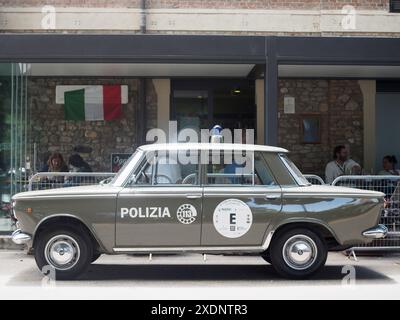 Castellarquato, Italien - 22. Juni 2024 Rallye mit Silberflagge, klassischer italienischer Fiat 1500 Polizeiwagen, der auf einer Straße der Stadt geparkt ist, und Leute sitzen draußen Stockfoto