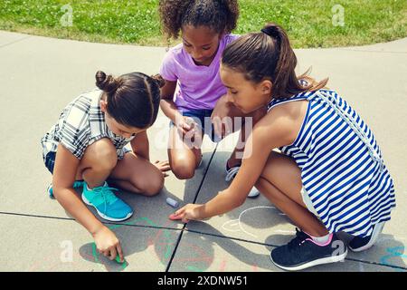 Mädchen, Schulkinder und Zeichnen am Boden mit Kreide für Lernen, Vielfalt und Kreativität. Gruppe, Kunst und Kinder bei Sonnenschein auf Bürgersteig, Weg oder Stockfoto