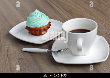 Creme Kuchen und eine Tasse Kaffee. Der Kuchen liegt auf einer Untertasse. In der Nähe eines Kaffeelöffels. Stockfoto