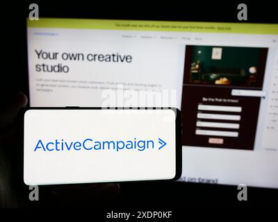 Person, die ein Smartphone mit dem Logo des US-amerikanischen Marketingsoftwareunternehmens ActiveCampaign LLC vor der Website hält. Schwerpunkt auf dem Display des Telefons. Stockfoto