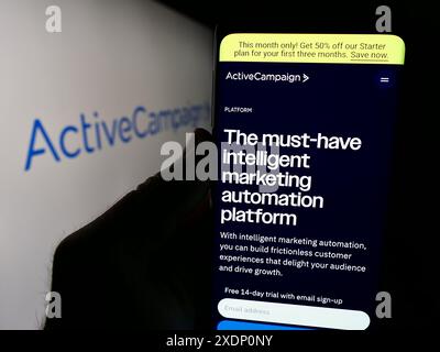 Person mit Smartphone und Webseite des US-amerikanischen Marketingsoftware-Unternehmens ActiveCampaign LLC vor dem Logo. Konzentrieren Sie sich auf die Mitte des Telefondisplays. Stockfoto