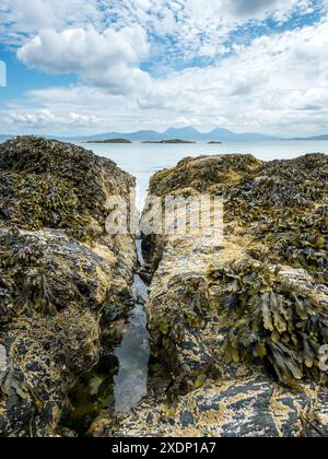 Der Paps of Jura ist am Horizont vom Port A Chapuill Strand auf der nahegelegenen Insel Colonsay in den Inneren Hebriden in Schottland, Großbritannien, zu sehen Stockfoto