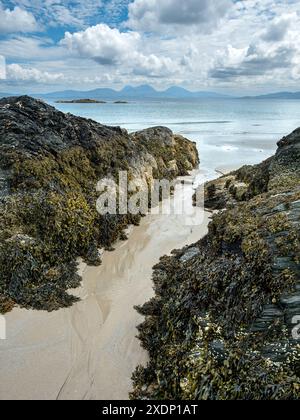 Der Paps of Jura ist am Horizont vom Port A Chapuill Strand auf der nahegelegenen Insel Colonsay in den Inneren Hebriden in Schottland, Großbritannien, zu sehen Stockfoto