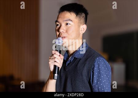 Ein junger Teenager hält ein Mikrofon in der Hand und hält eine Rede Stockfoto