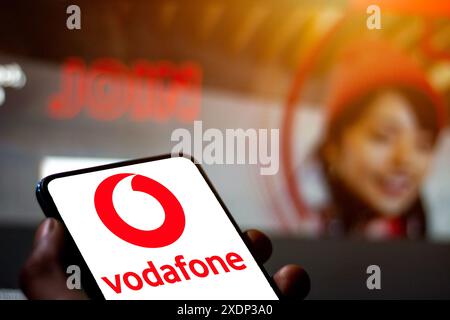 Foto-Illustration einer Männerhand mit dem Logo des britischen multinationalen Telekommunikationsunternehmens Vodafone auf einem Handy-Bildschirm. Stockfoto