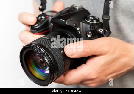 Nahaufnahme einer Person, die ein Kameraobjektiv anpasst, während sie eine Digitalkamera hält. Stockfoto