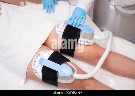 Professionelle Elektrostimulation-Sitzung, Nahaufnahme von Therapeutin, die EMS-Gerät auf Frau in der modernen Klinik anwendet, Muskeltonisierung, Körpermodellierung Stockfoto