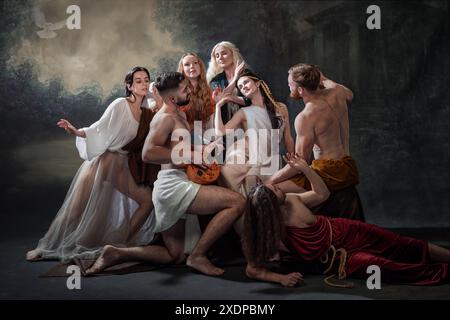 Zusammenkunft der Seelen. Eine Gruppe von Menschen, die in fließenden Gewändern gekleidet sind, versammeln sich um einen Mann, der Laute vor nebeligem, bewaldetem Hintergrund spielt. Stockfoto