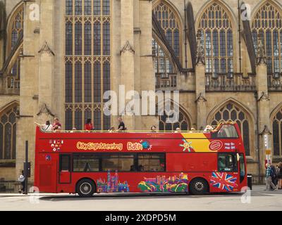 Toot Bus Hop-on-Hop-off-Bus mit geführter Stadtbesichtigung, in dem Personen in den Bus steigen und aus dem Bus steigen, und Bath Abbey im Hintergrund. Bath, Somerset, Großbritannien Stockfoto