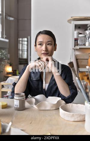 Asiatische Künstler glasieren und malen Tongeschirr mit Pinsel Stockfoto