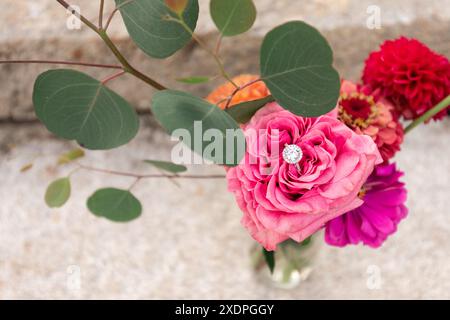 Diamant-Ring in einem lebhaften Bouquet aus gemischten Blumen und Blättern Stockfoto