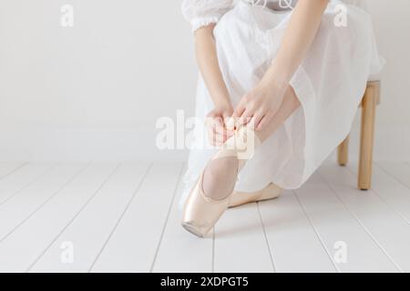 Ballerina zieht ihre spitzenschuhe im weißen Studio aus Stockfoto