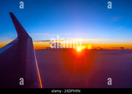 Wing View of Sunrise Silhouette of Wolken from the Airplane. Stockfoto