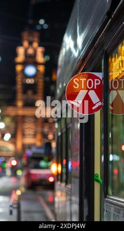 Halten Sie Schild mit der Straßenbahn von Melbourne in der Stadt bei Nacht Stockfoto