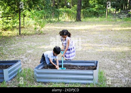 Zwei Kinder, die im Garten in Hochbeeten im Freien arbeiten Stockfoto