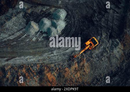 Bagger bei Arbeit auf dunklem Hintergrund. Draufsicht von einer Drohne Stockfoto