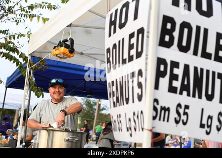 Lächelnder Anbieter, der heißgekochte Erdnüsse auf einem Markt im Freien verkauft. Stockfoto