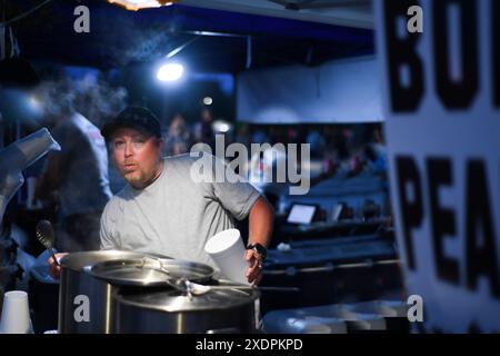 Verkäufer auf einem Nachtmarkt, der heiße gekochte Erdnüsse mit einem Aufschlag serviert Stockfoto