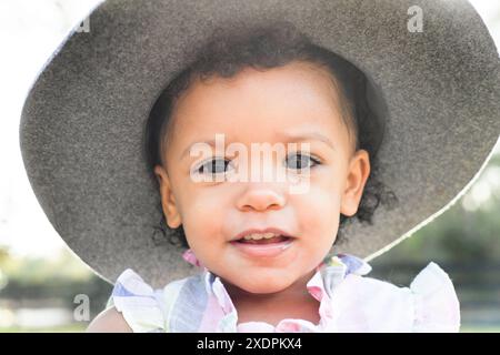 Nahaufnahme eines Kleinkindes, das einen Hut trägt und draußen lächelt. Stockfoto