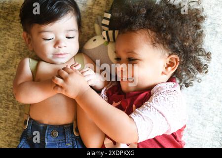 Zwei Kinder liegen zusammen, lächeln und halten die Hände. Stockfoto