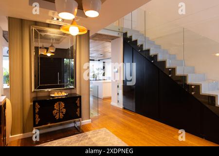 Moderne Inneneinrichtung mit stilvollem Treppenhaus und eleganten Möbeln im Flur Stockfoto