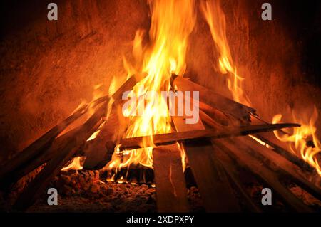 Grillzubereitung mit Brennholz im Inneren. Holzkohleverbrennung im Grill oder im Rahmen. Holzscheite vor dem Feuergrill. Holzscheite brennen draußen im Feuergrill. F Stockfoto