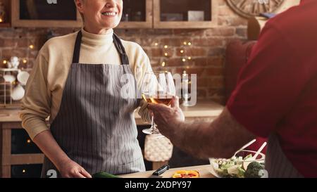 Geerntet von Seniorenpaar, das mit Wein in einer Küche toast Stockfoto